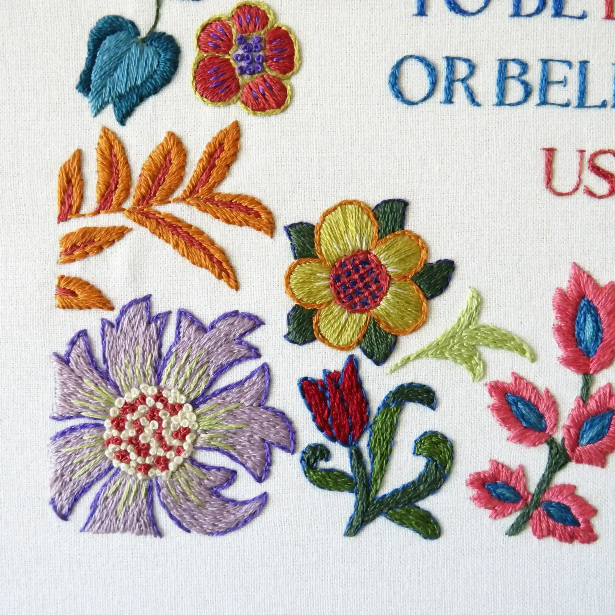 Embroidered floral design with colorful flowers and leaves on a white background.