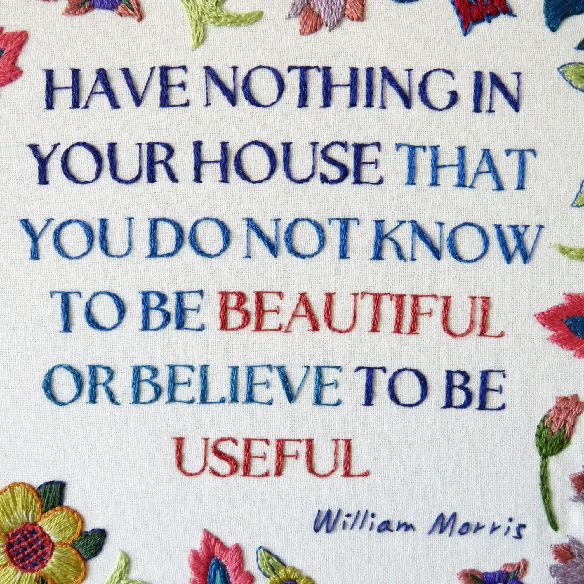 Embroidered quote with colorful flowers on a white background