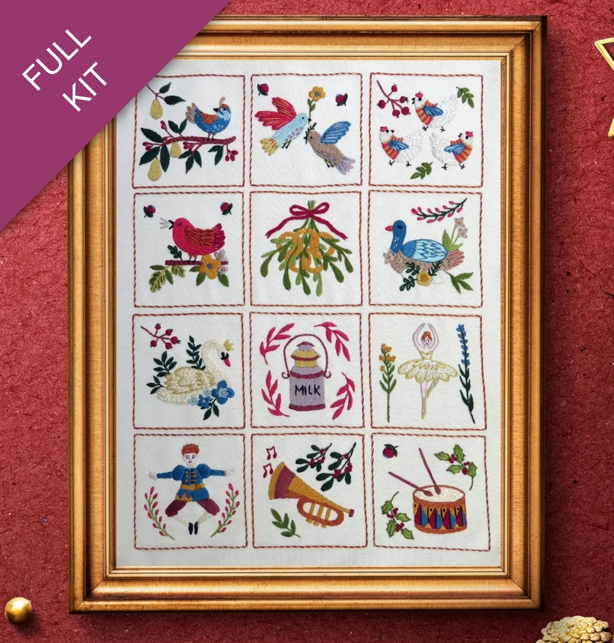 Framed cross-stitched sampler with various designs on a red background