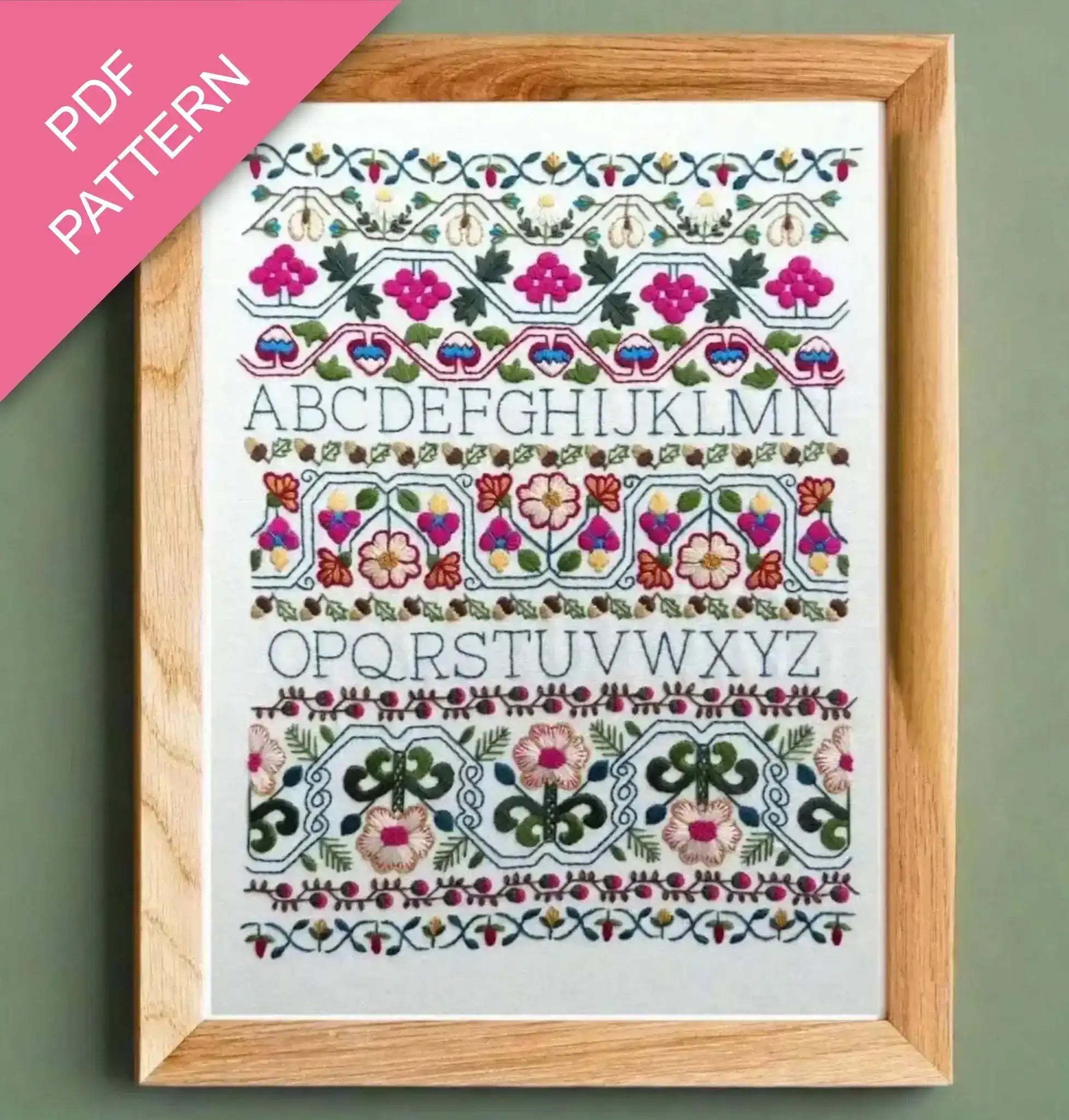 Embroidery pattern with floral designs and letters framed on a green background