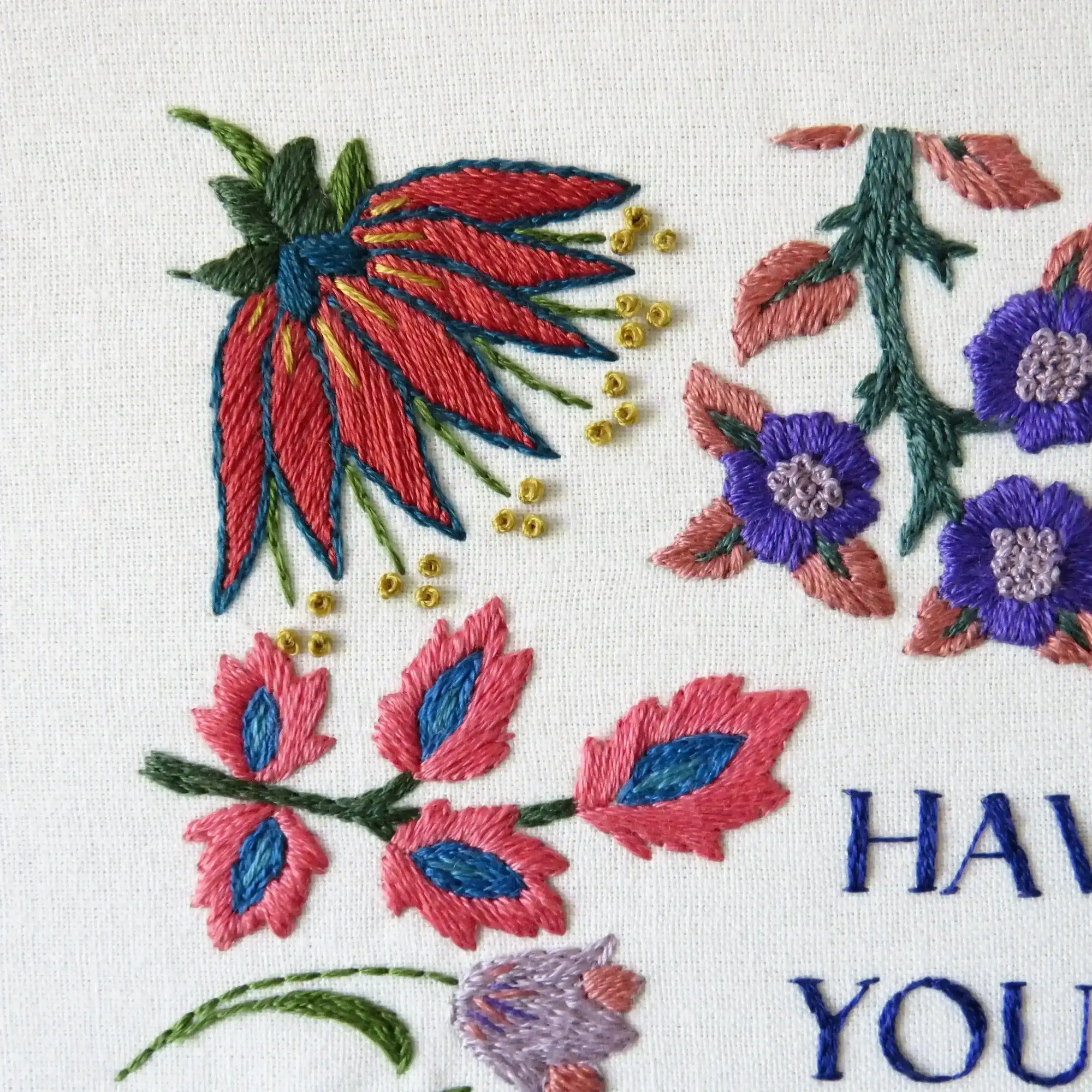 Embroidered floral design with colorful flowers and leaves on a white background.