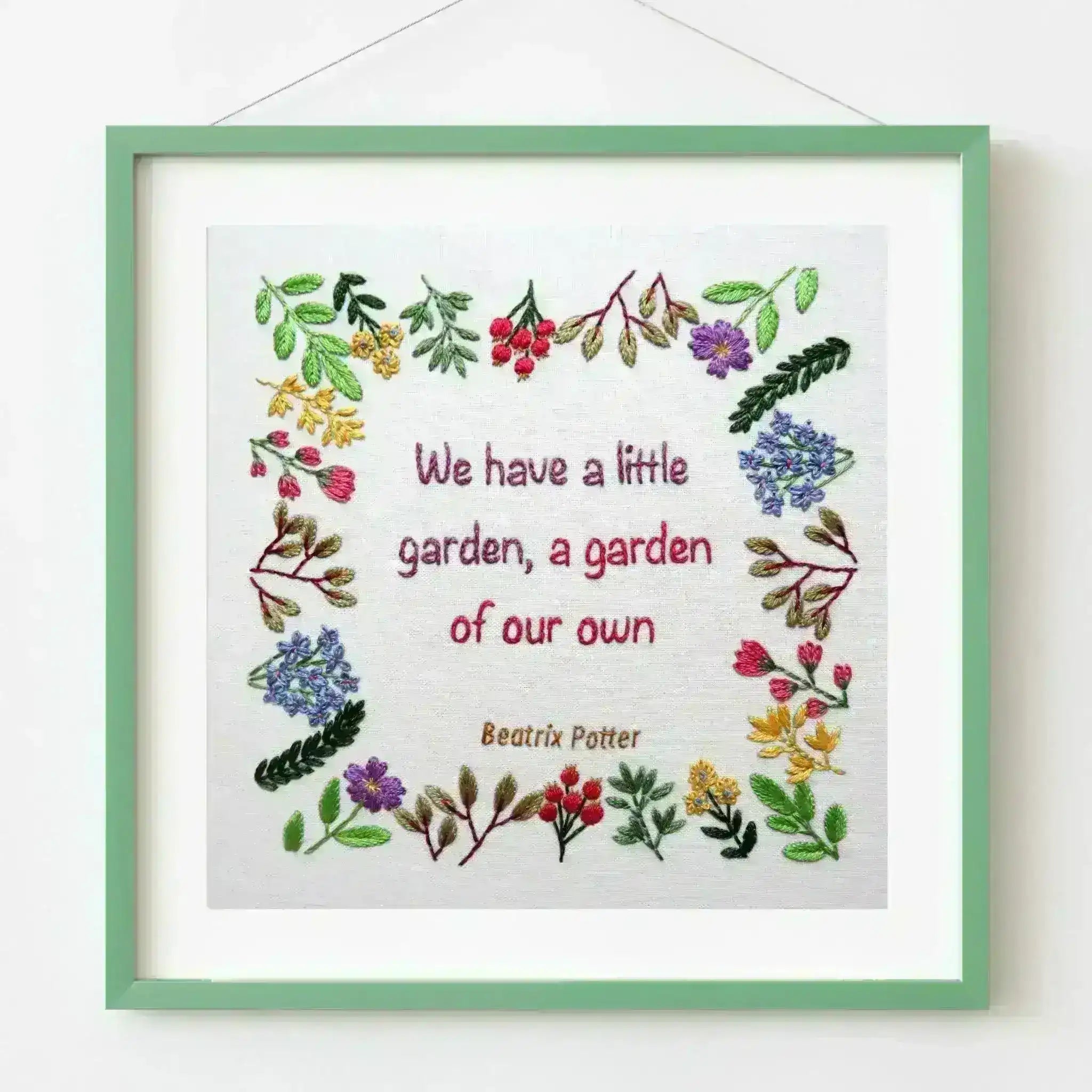 Framed embroidery with floral designs and text on a white background