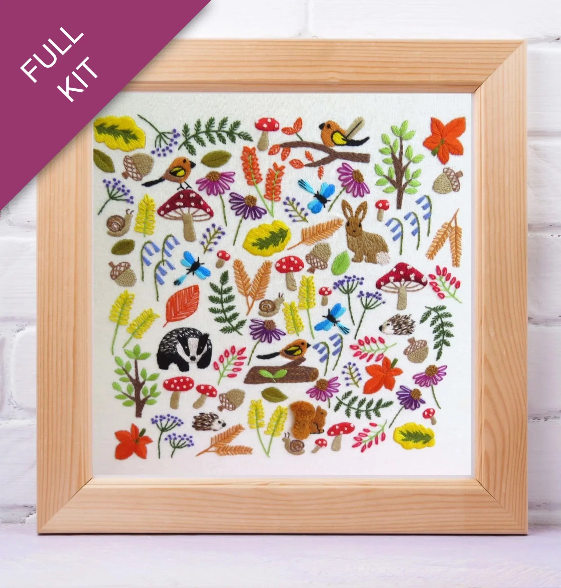 Framed embroidery kit with colorful forest-themed design on a white background