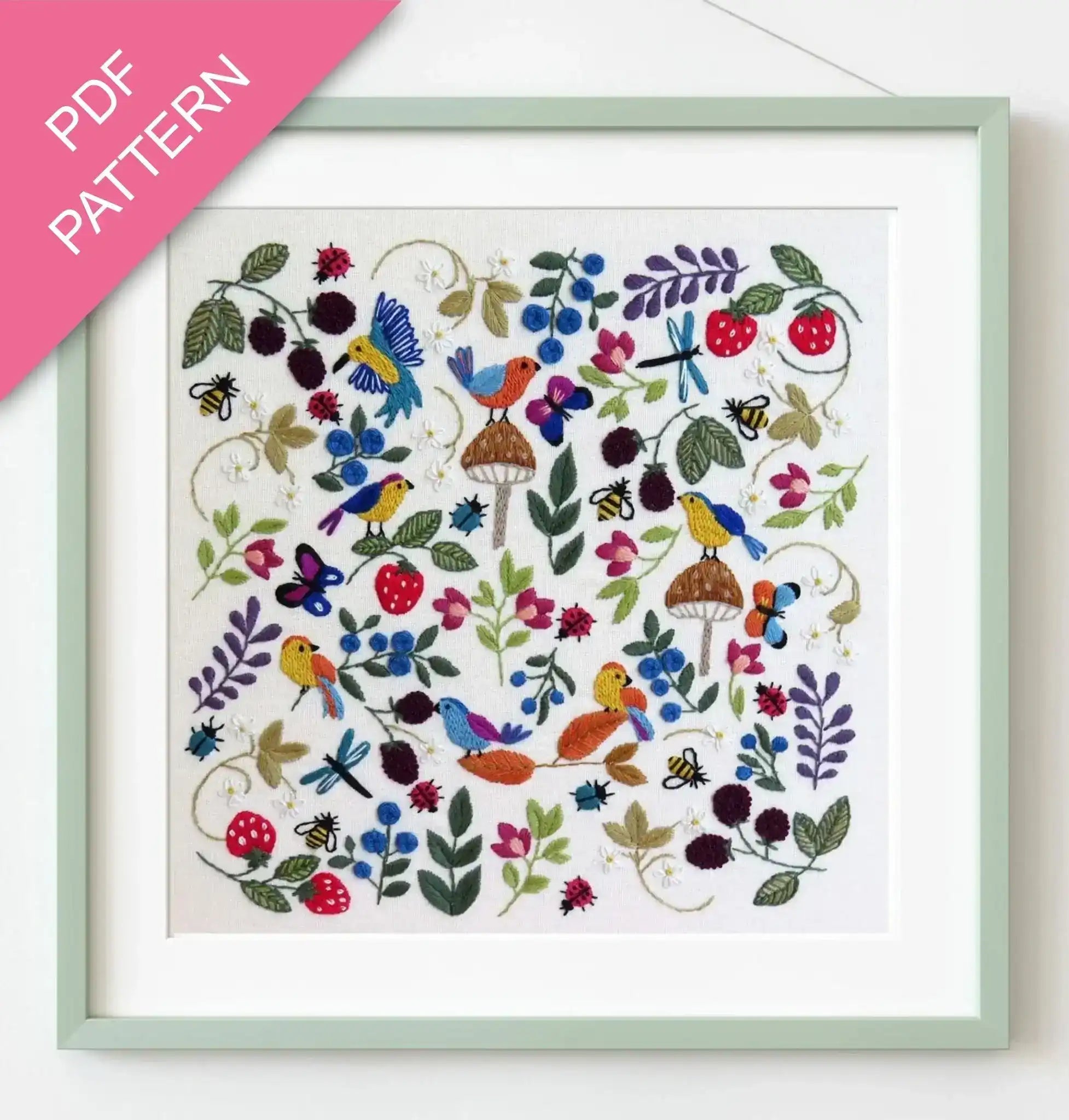 Embroidery pattern with colorful birds and flowers in a green frame.
