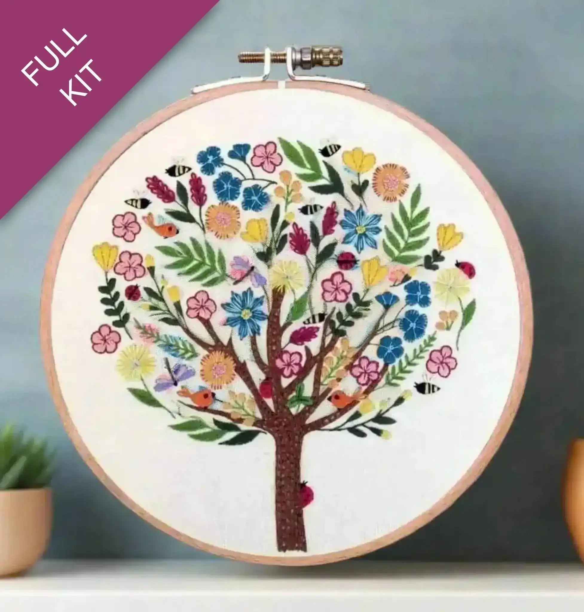 Embroidery hoop with a colorful tree design on a gradient background