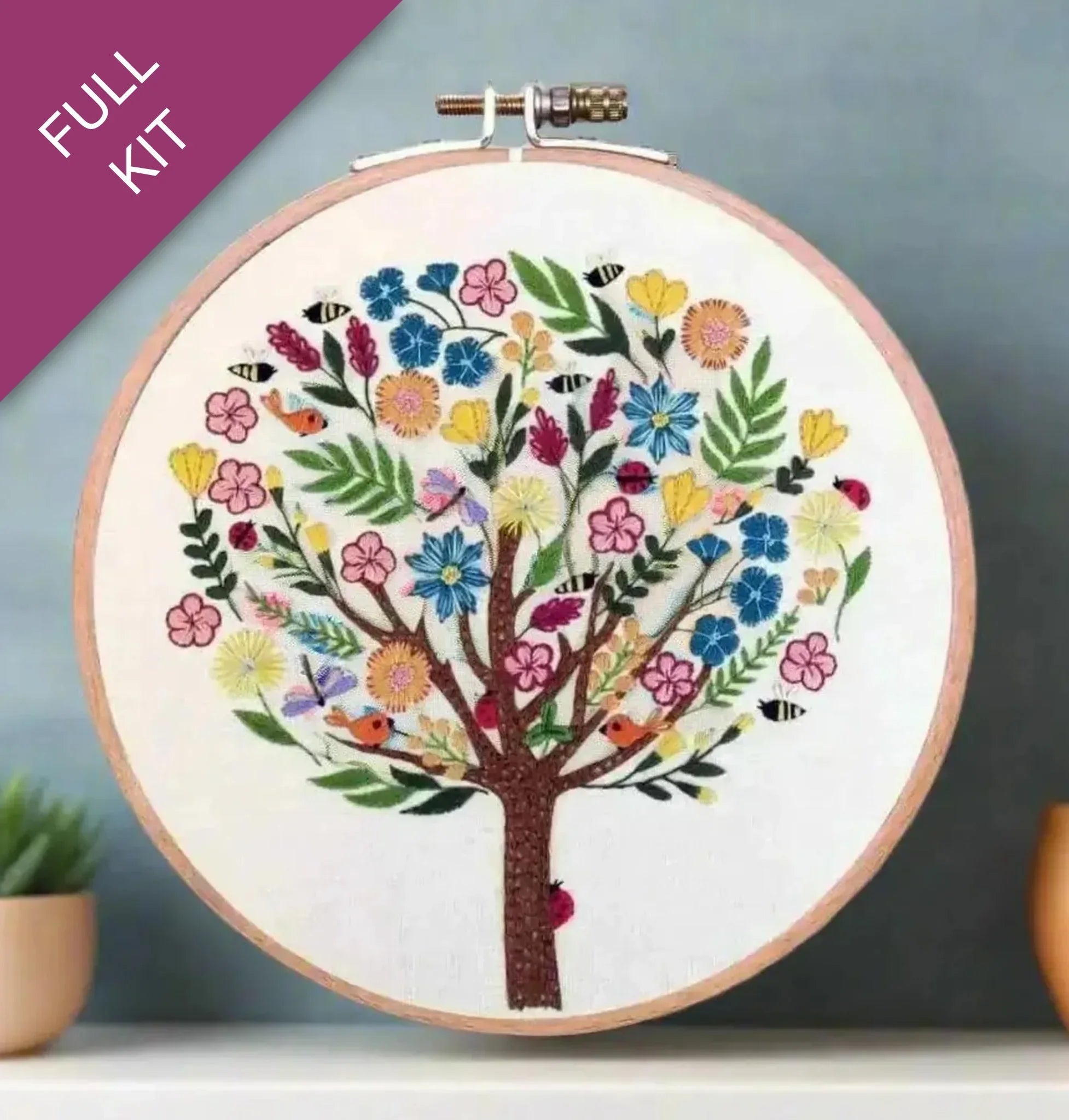 Embroidery hoop with a colorful tree design on a gradient background