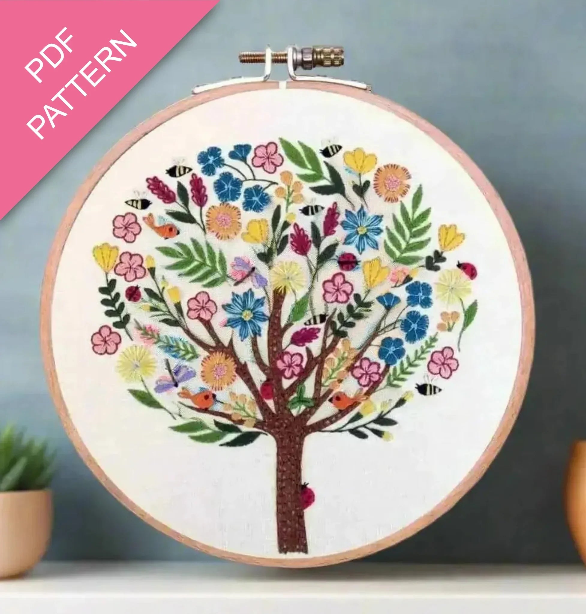 Embroidery hoop with a colorful tree design on a white background