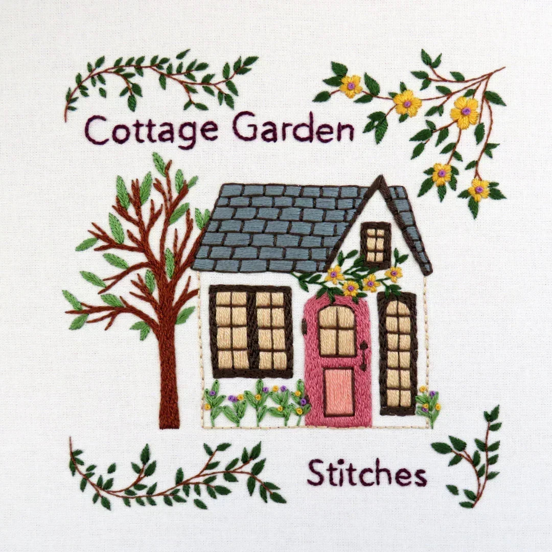 Embroidered design of a cottage with trees and flowers, labeled 'Cottage Garden Stitches'.