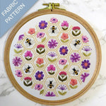 Embroidery hoop with floral and bee pattern on a marble surface