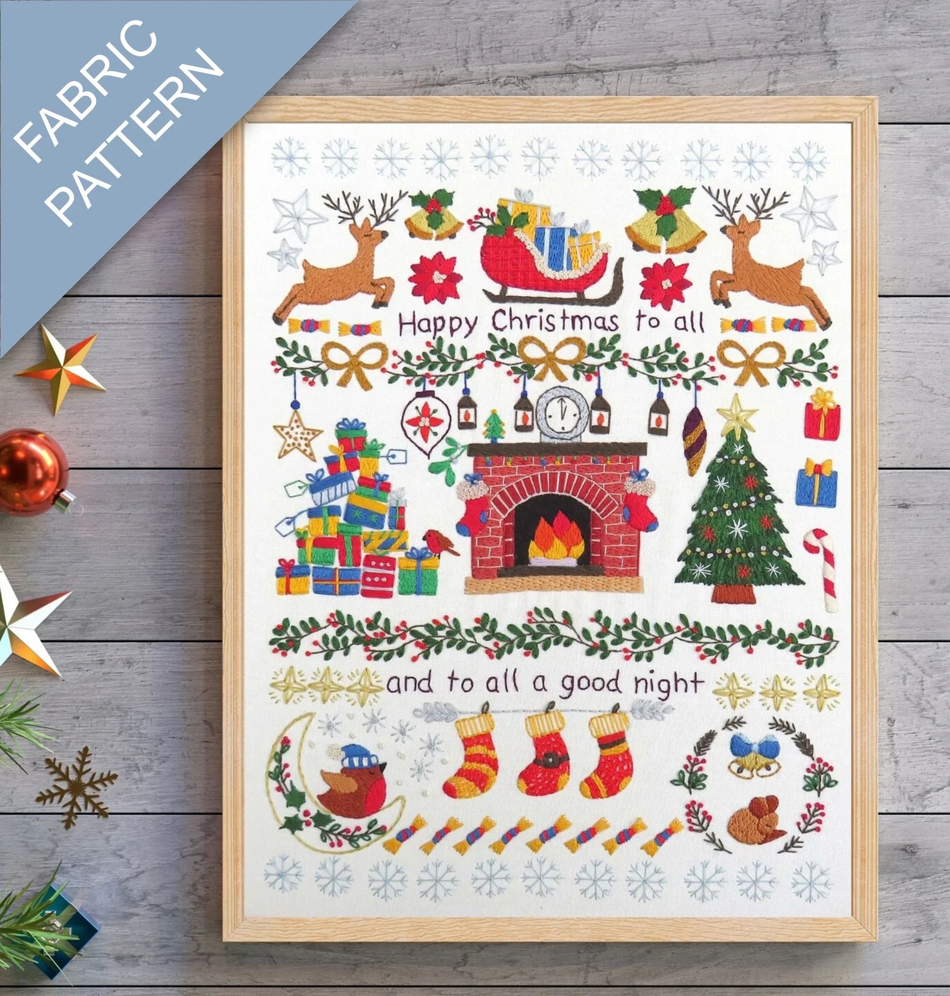 Framed Christmas-themed fabric pattern with Santa's sleigh, reindeer, and fireplace on a wooden surface.