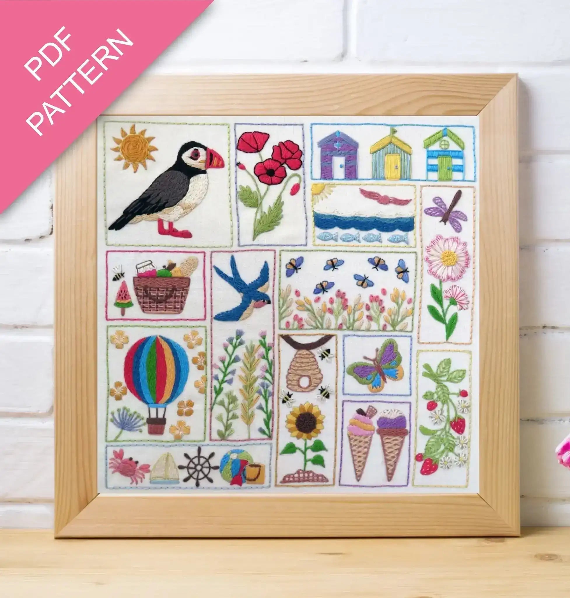 Framed embroidered sampler with various designs including a puffin, flowers, and animals on a white background.