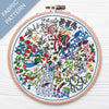 Embroidery hoop with a colorful fabric pattern featuring birds and trees on a white background.
