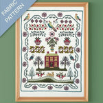 Framed fabric pattern with a house, trees, and birds design on a green background