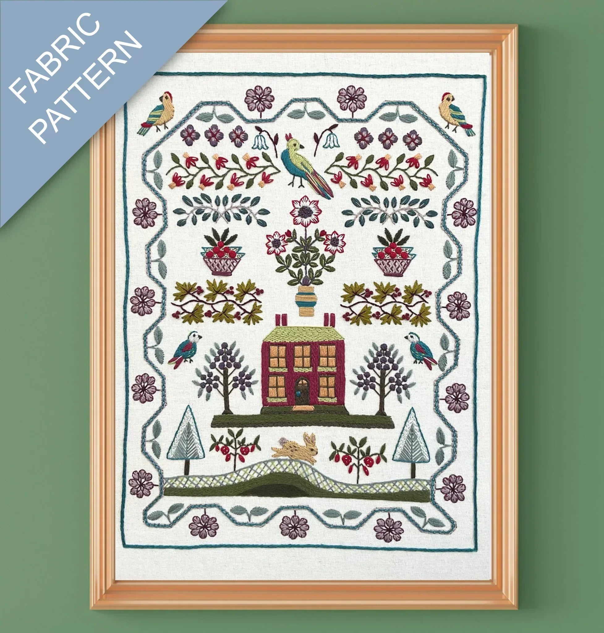 Framed fabric pattern with a house, trees, and birds design on a green background