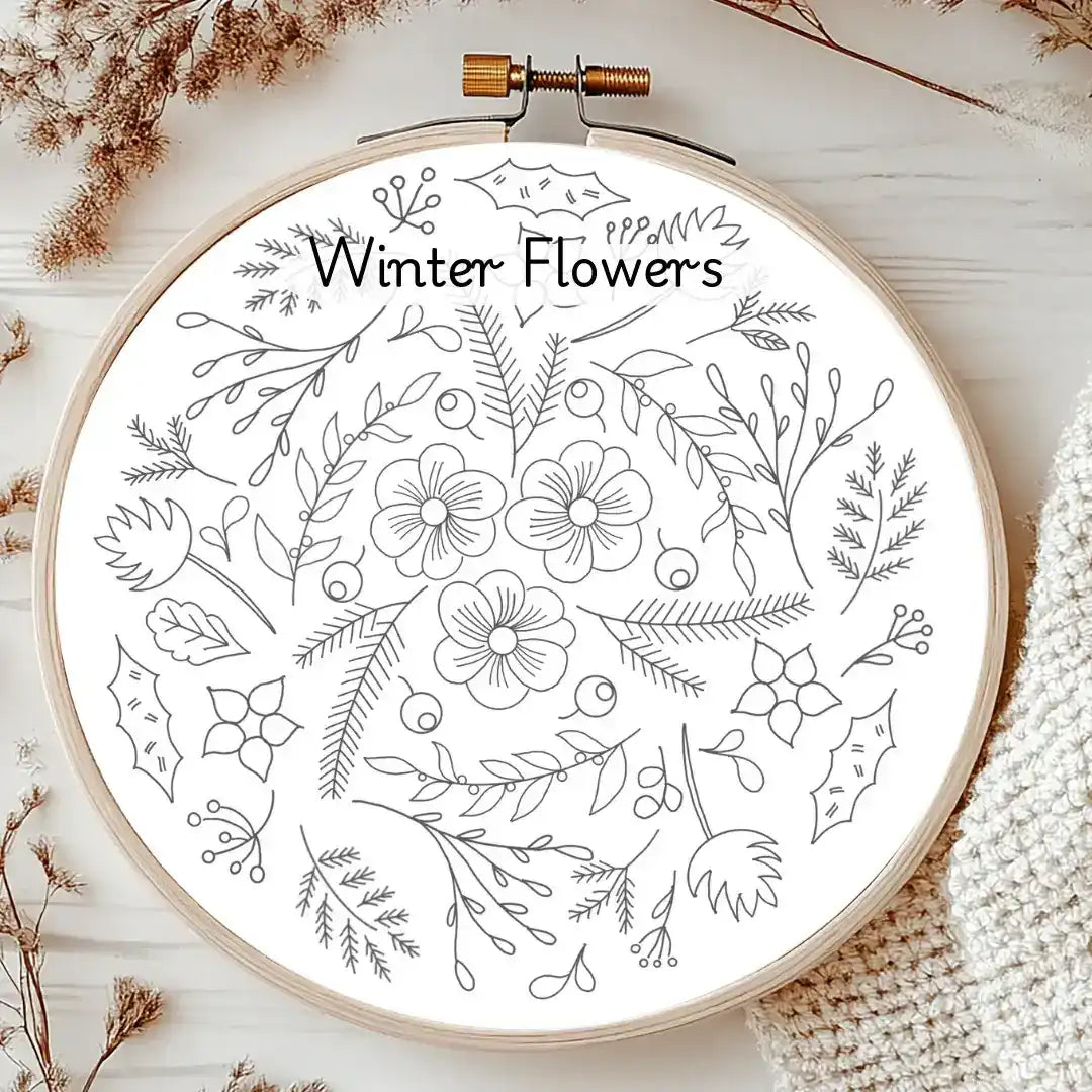 Embroidery hoop with 'Winter Flowers' design on a wooden surface.