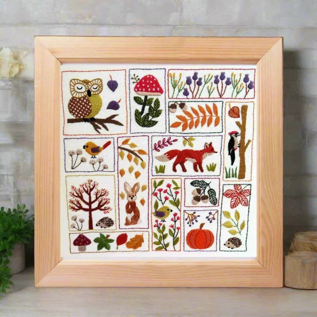 Framed embroidery with nature-themed designs on a white background