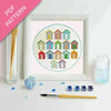 Embroidery kit with colorful beach hut design, thread, and tools on a white background.