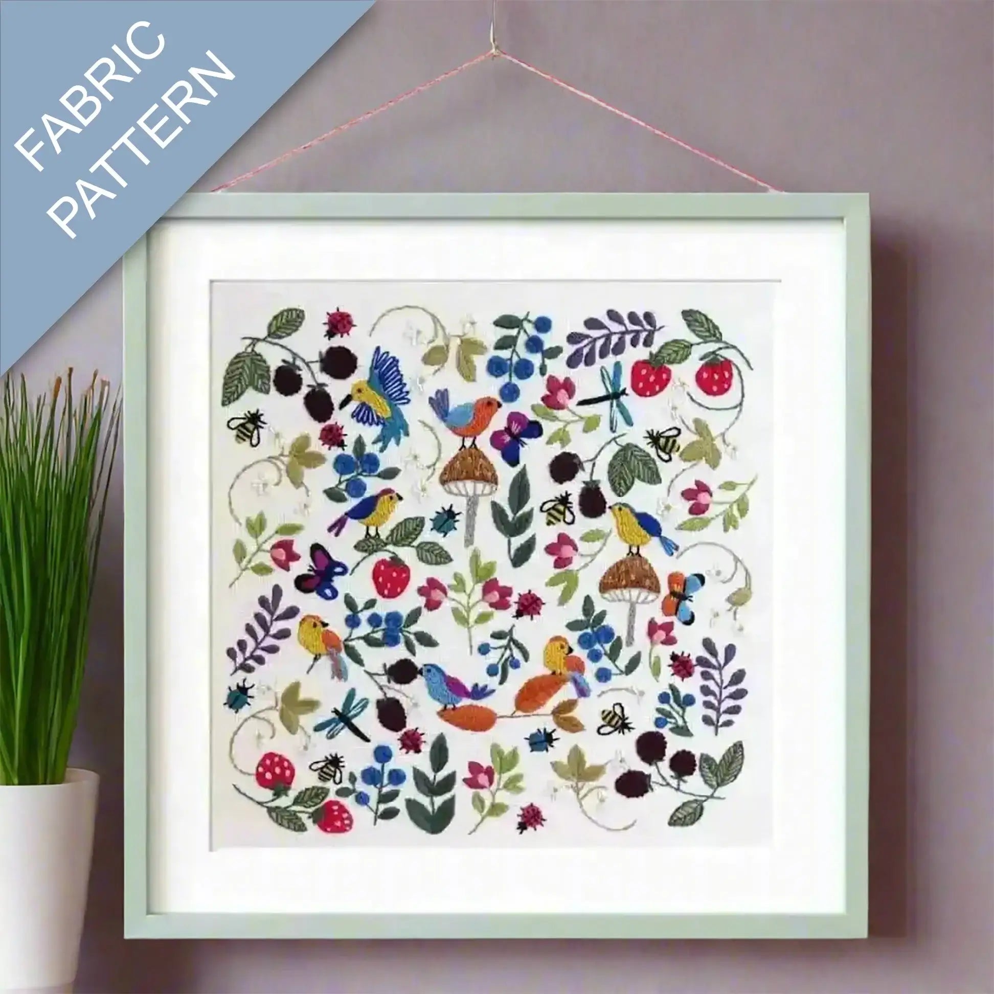 Framed fabric pattern with colorful birds and flowers on a wall.
