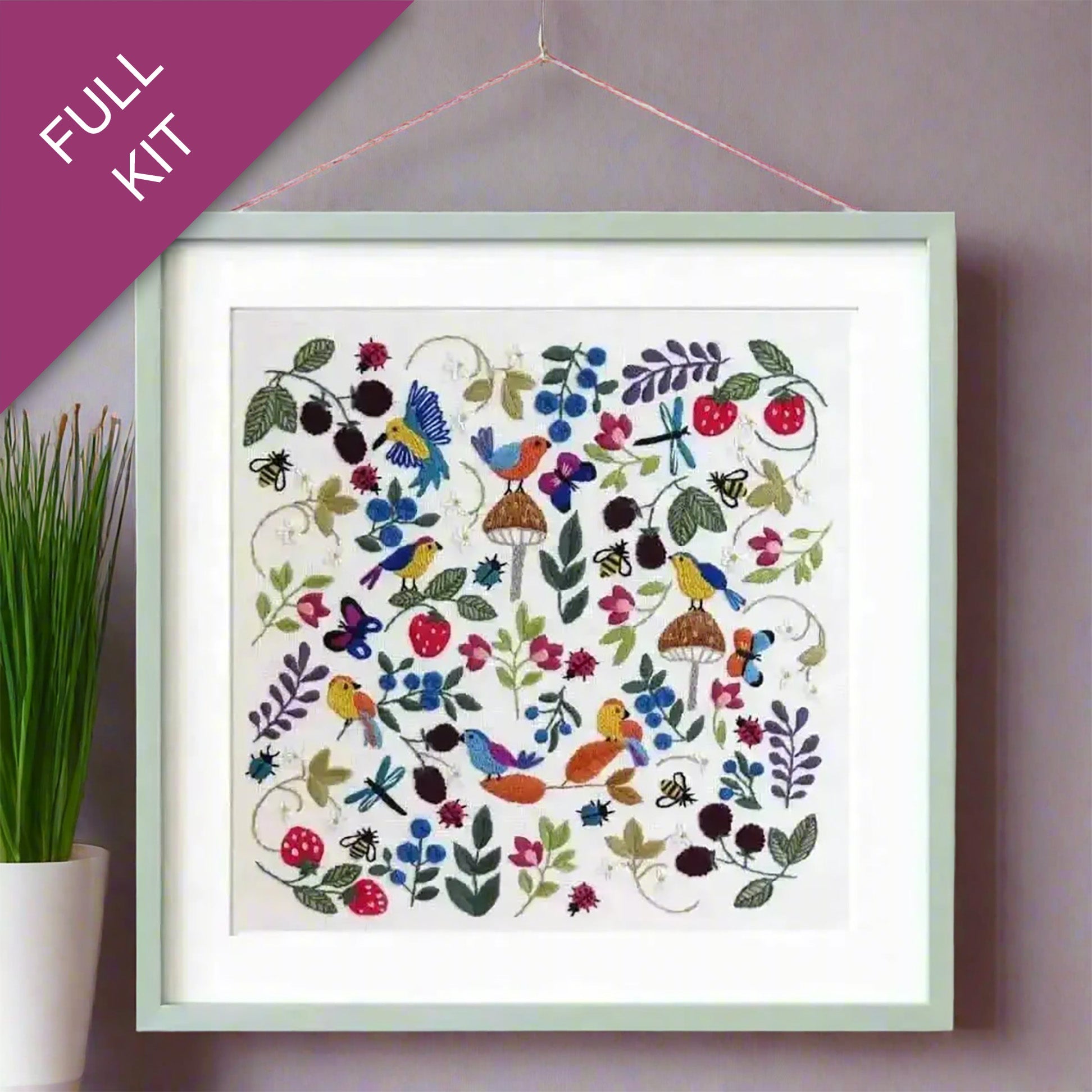 Embroidery kit with colorful design of birds, flowers, and fruits on a white background.