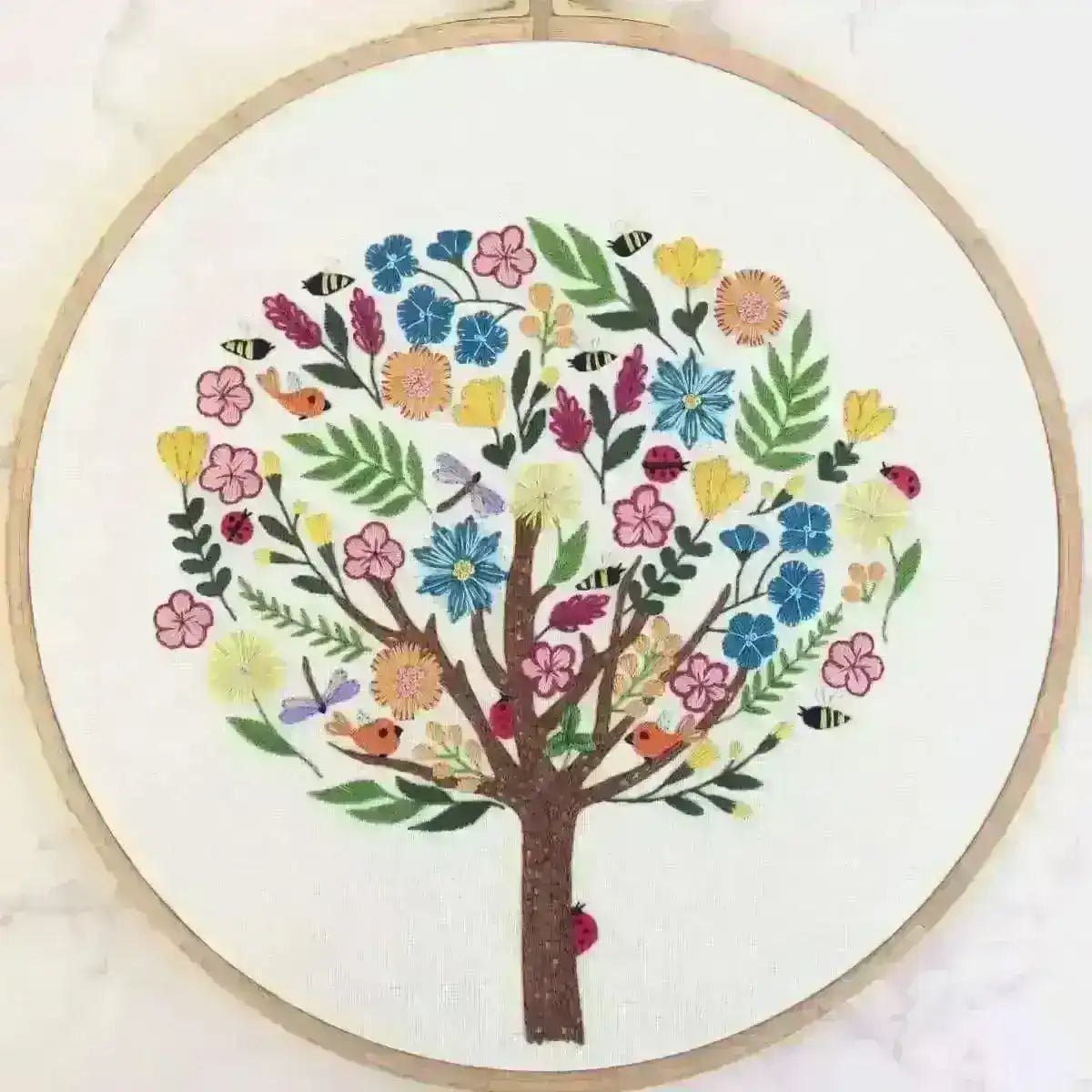 Embroidery hoop with a colorful tree design on a white background