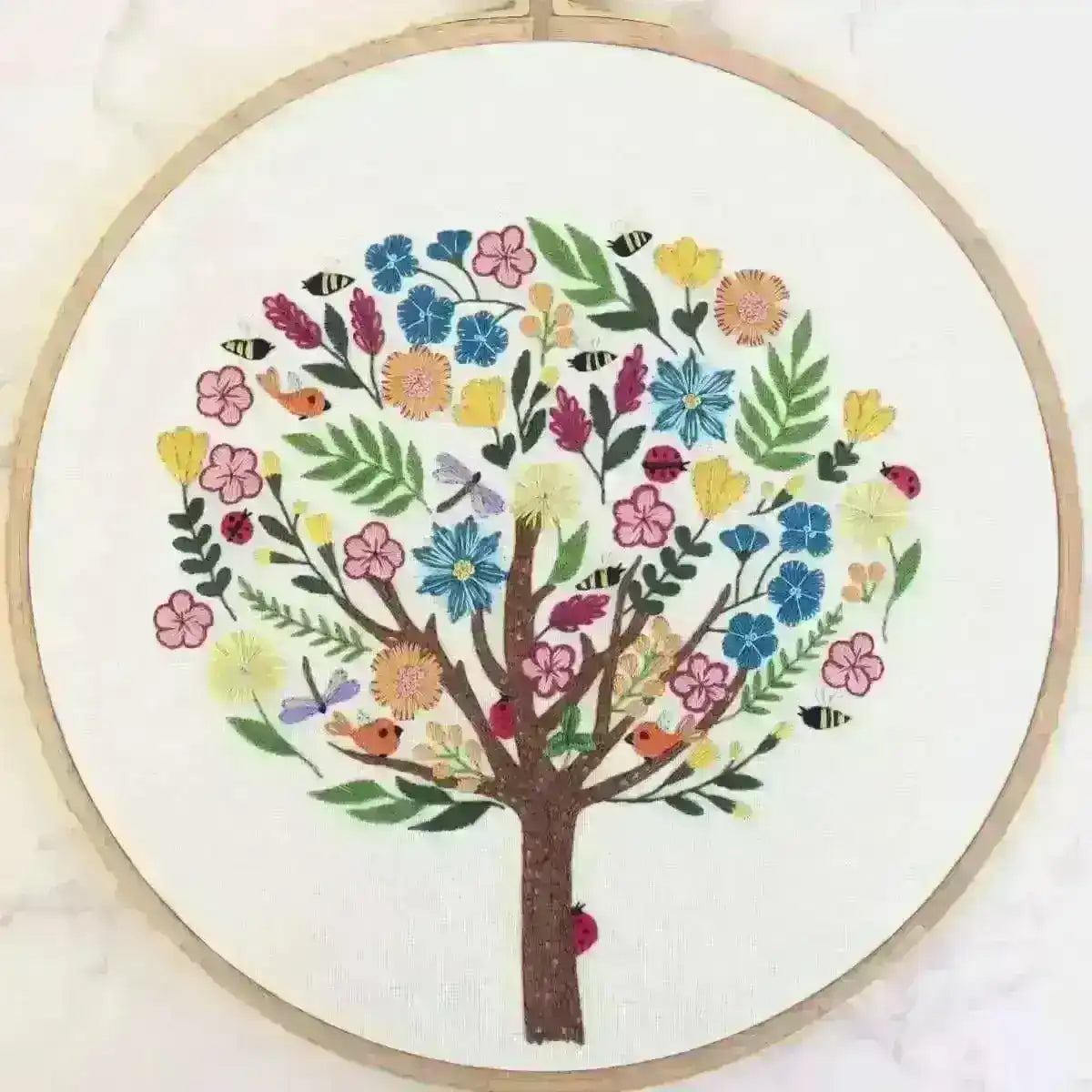 Embroidery hoop with a colorful tree design on a white background