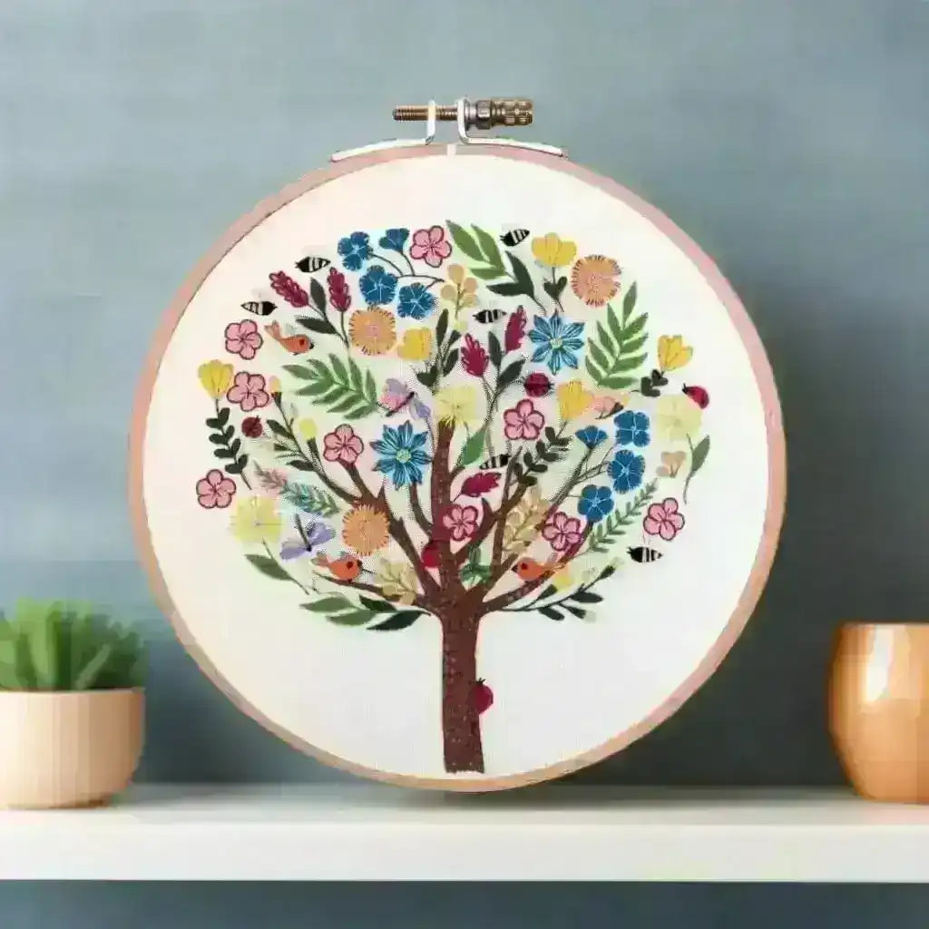 Embroidery hoop with a colorful floral and bird design on a plain background