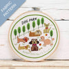 Embroidery hoop with 'Dog Park' design featuring cartoon dogs and trees on a wooden surface.