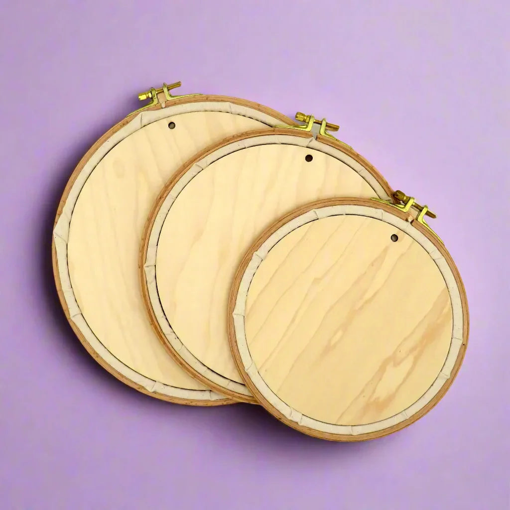 Three wooden embroidery hoops on a purple background