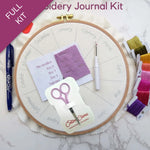 Embroidery kit with supplies including an embroidery hoop, scissors, and thread on a marble surface.