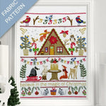 Framed fabric pattern with Christmas-themed design featuring a cabin, animals, and festive elements.