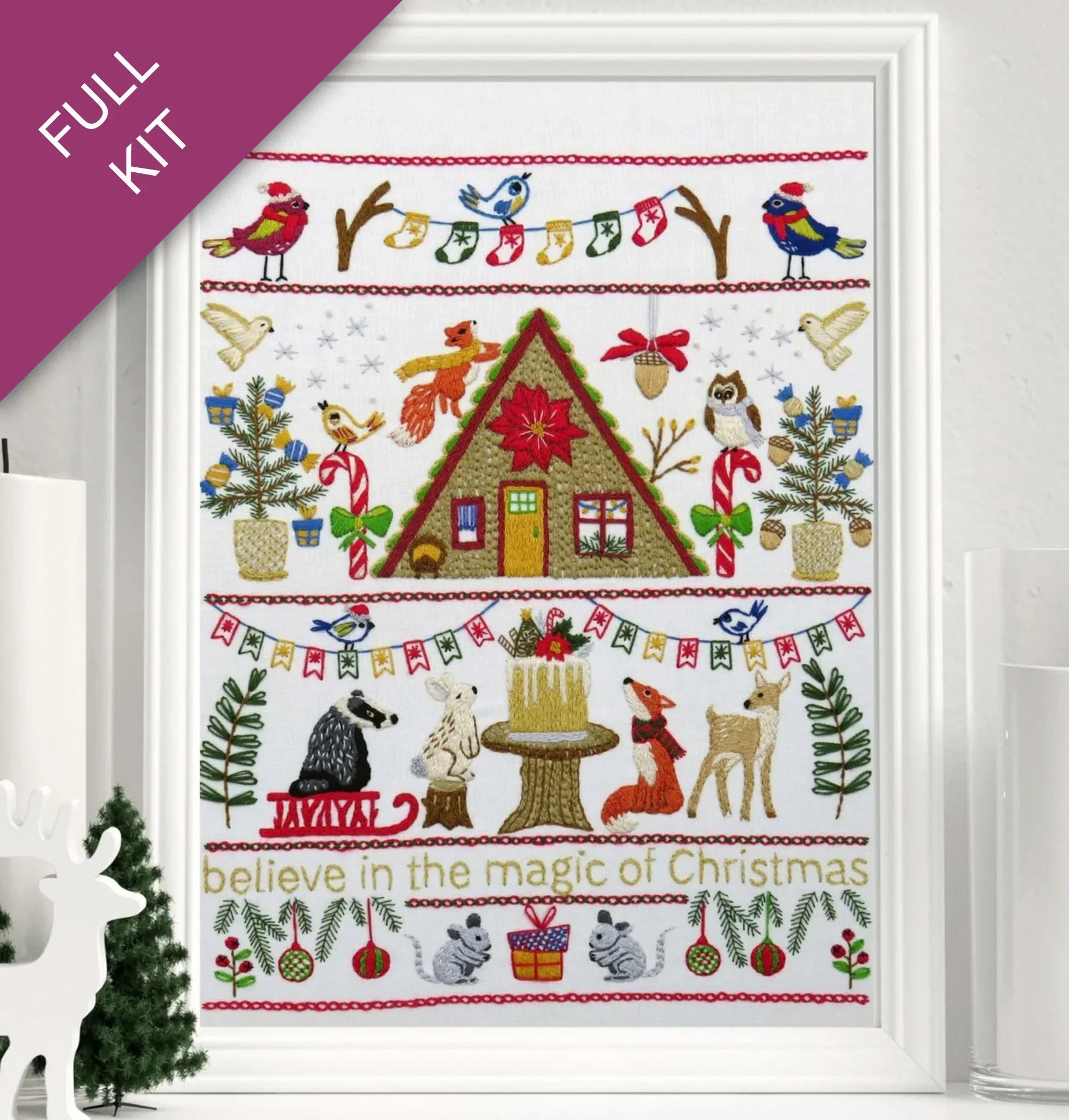 Embroidery kit with Christmas-themed design featuring a cabin, animals, and festive elements.