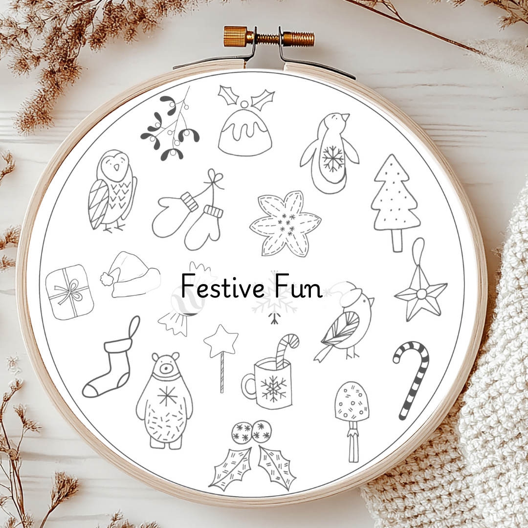 Embroidery hoop with black and white festive illustrations on a wooden surface.