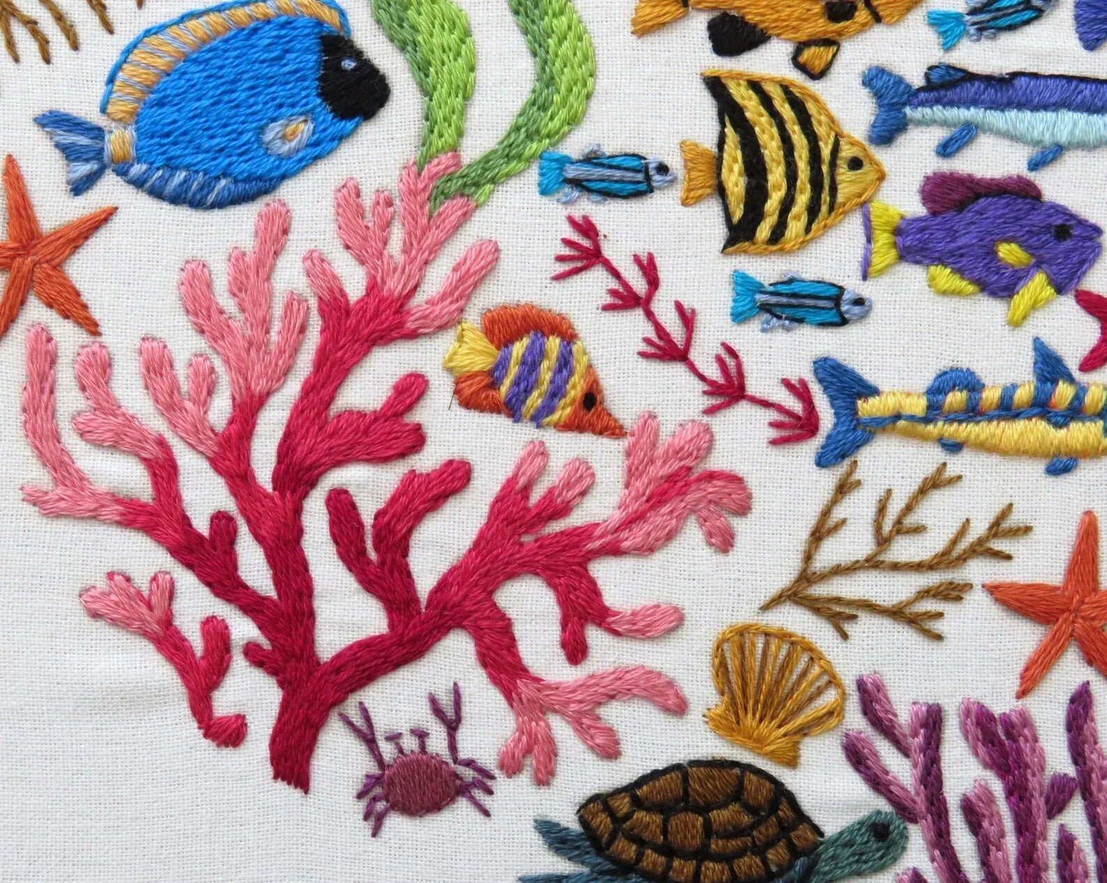 Embroidered design of colorful fish and coral on a white background