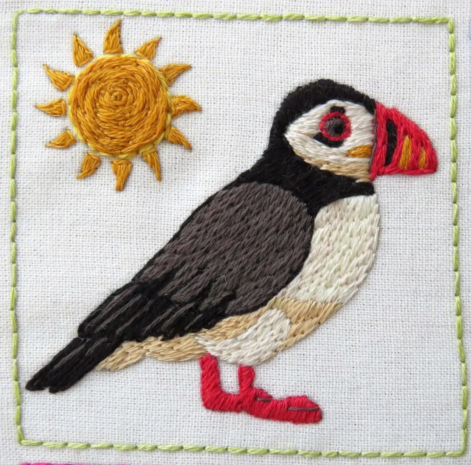 Embroidered puffin with a sun on a white background