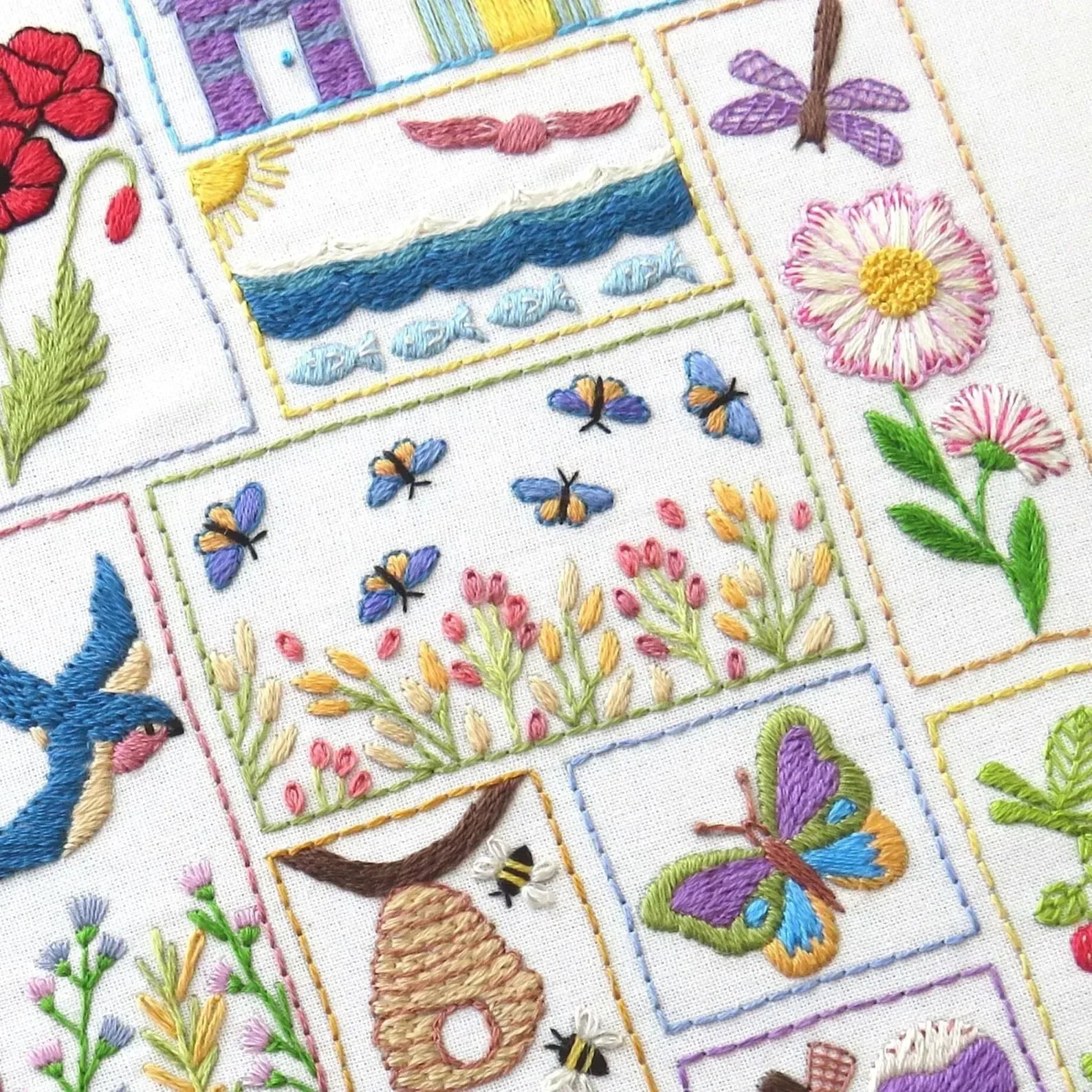Embroidered patchwork design with flowers, butterflies, and other nature-themed elements on a white background.