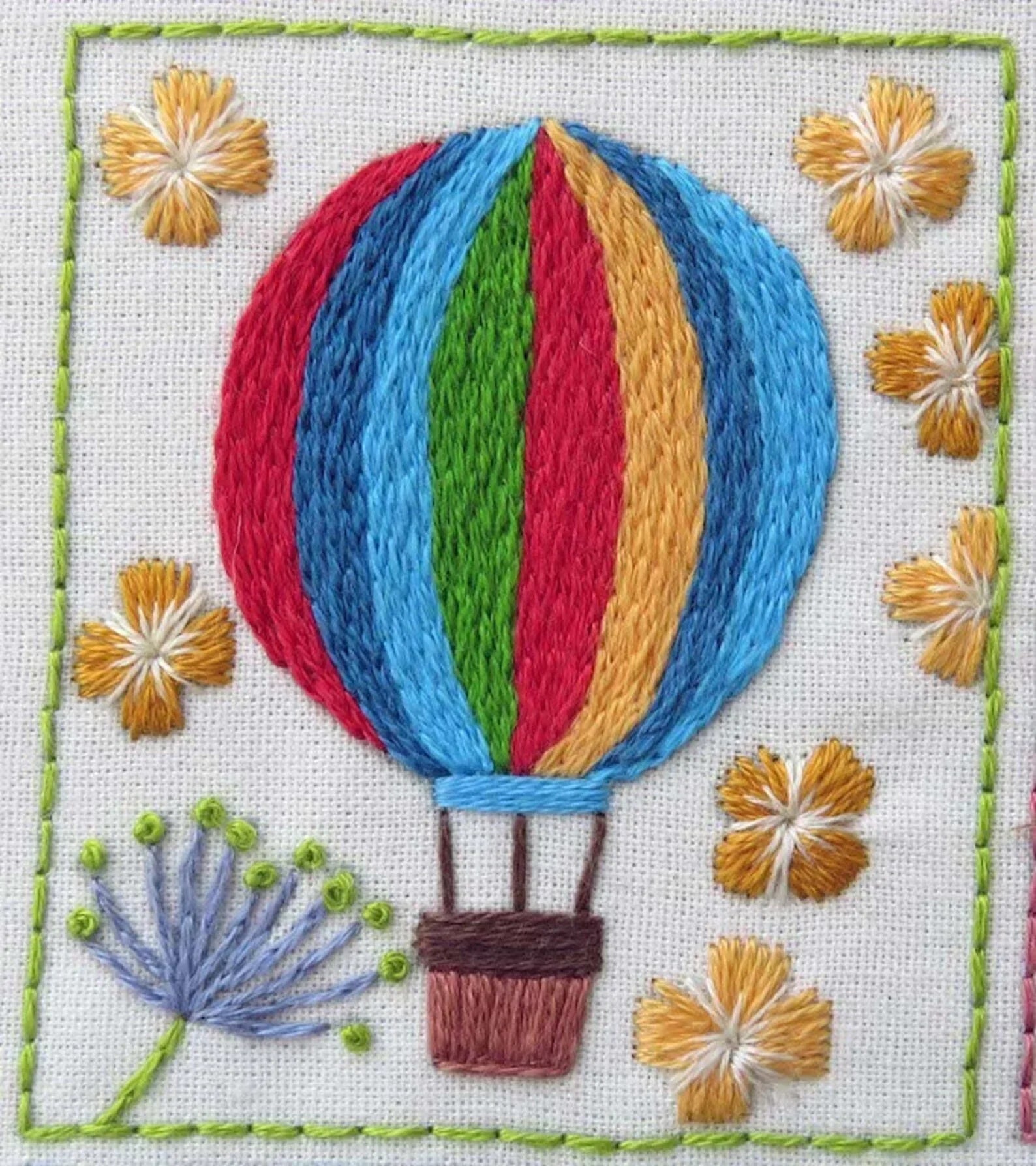 Embroidered design of a hot air balloon with flowers around it on a white background