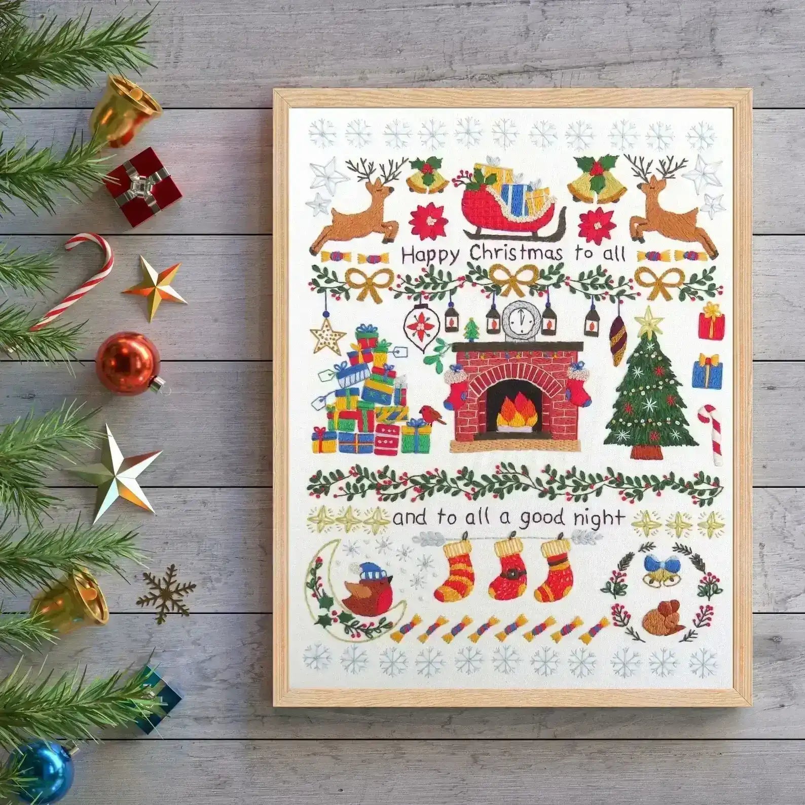 Framed Christmas-themed artwork with decorative elements on a wooden surface.