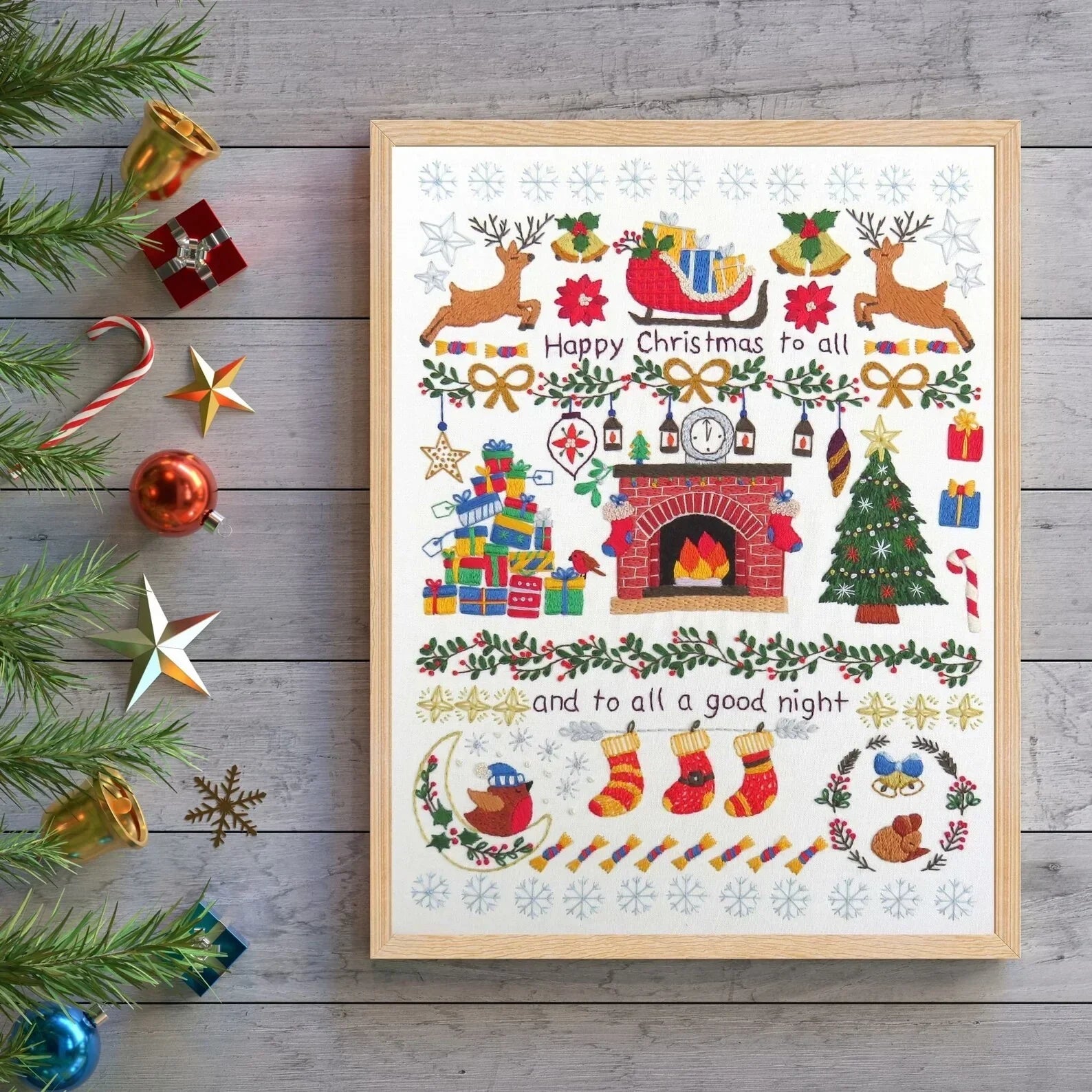 Framed Christmas-themed artwork with decorative elements on a wooden surface.