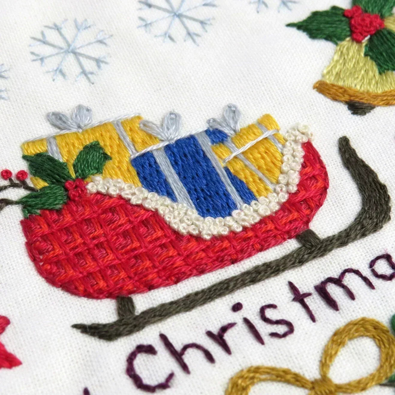 Embroidered design of a Christmas sleigh with colorful details on a white background.
