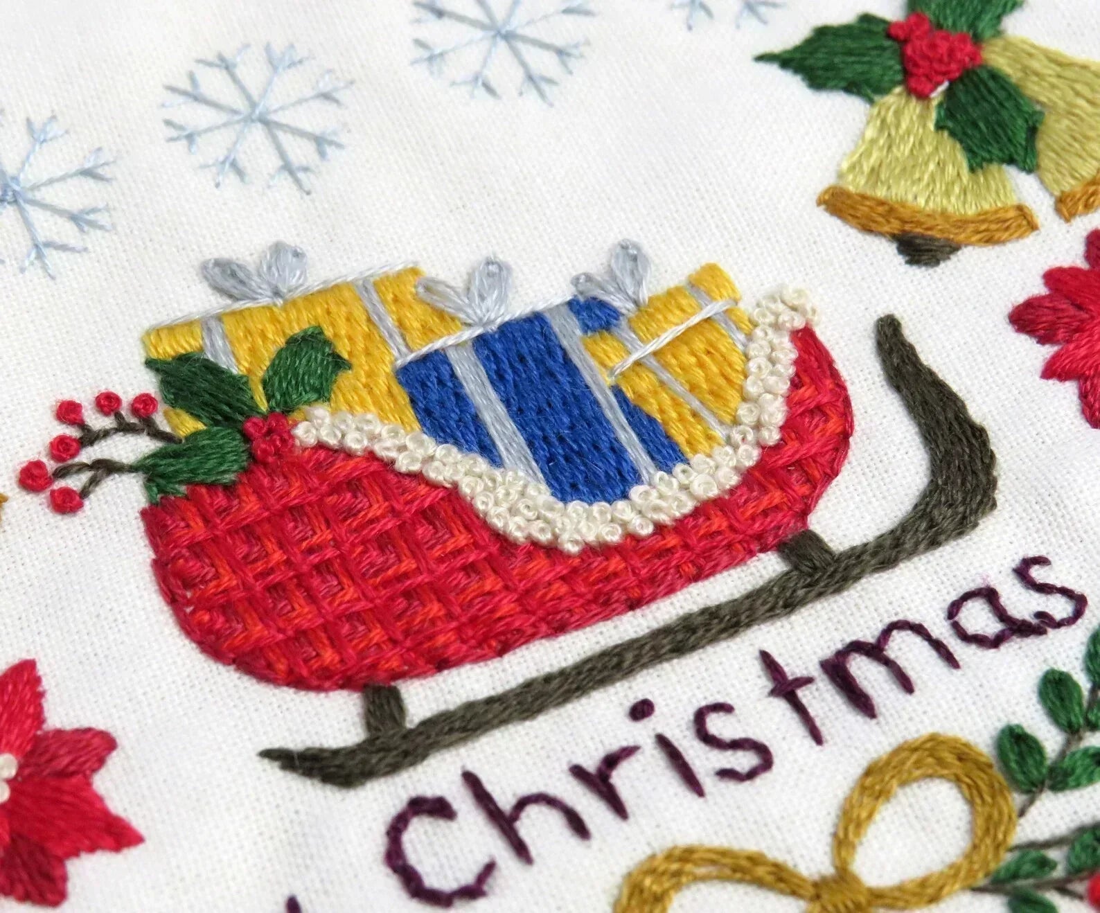 Embroidered design of a Christmas sleigh with colorful details on a white background.