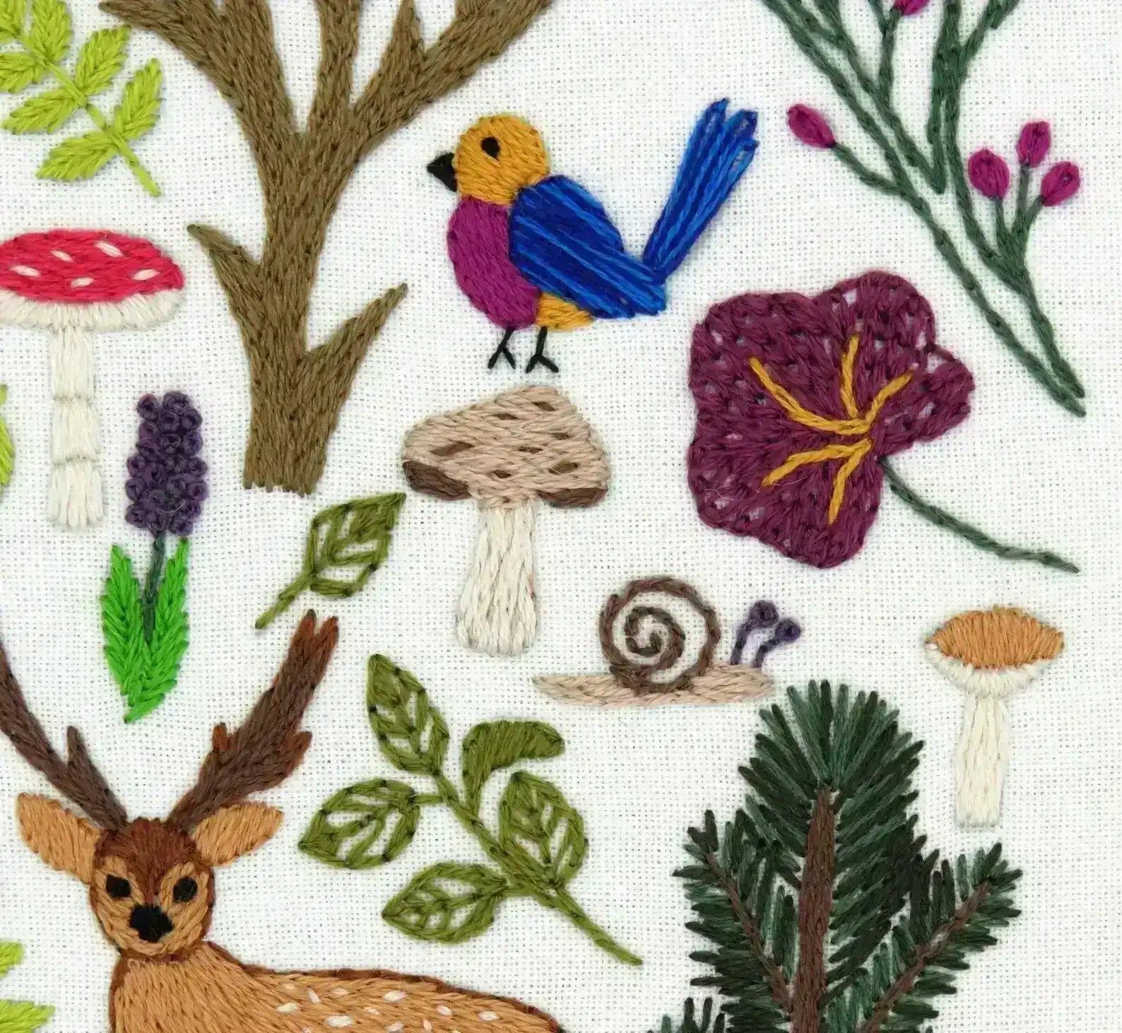 Embroidered design with deer, flowers, mushrooms, and plants on a white background