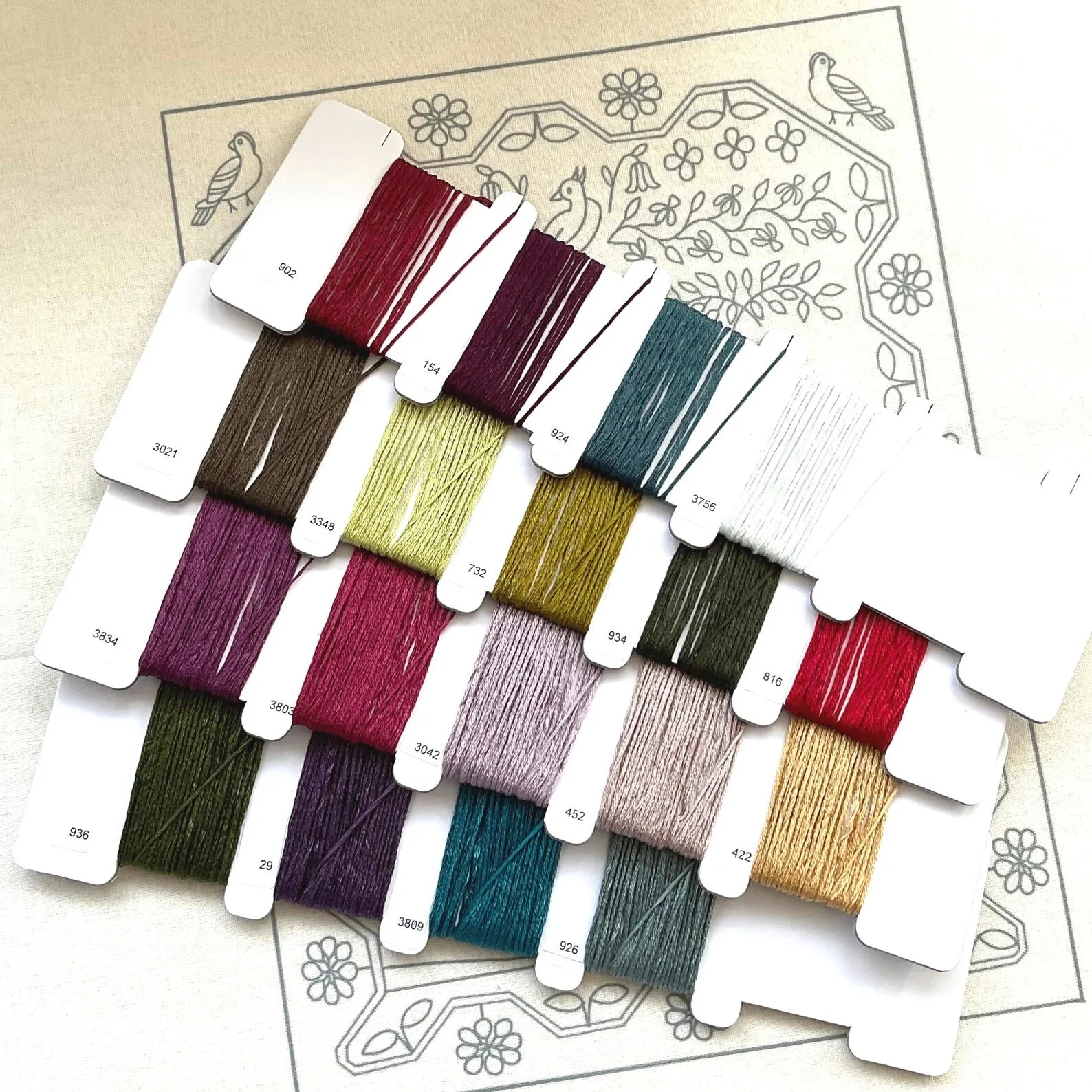 Set of embroidery thread samples with color swatches on a decorative paper background