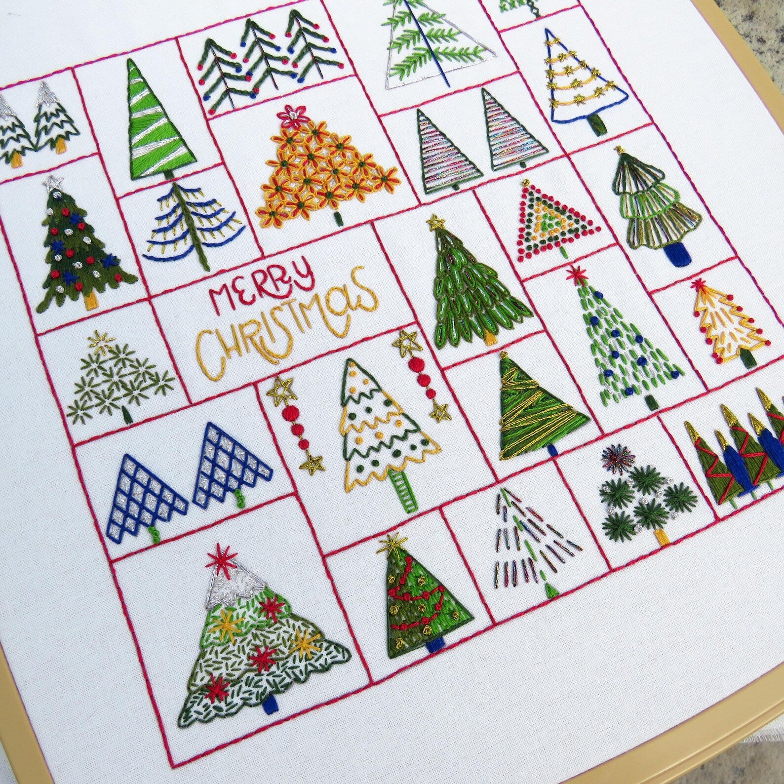 Embroidered Christmas trees on a white fabric with 'Merry Christmas' text.