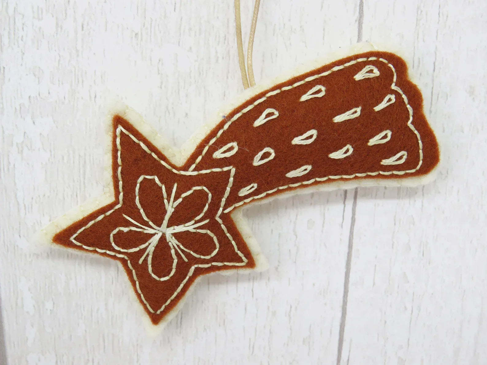 Decorative star-shaped cookie with white floral design on a light wooden surface