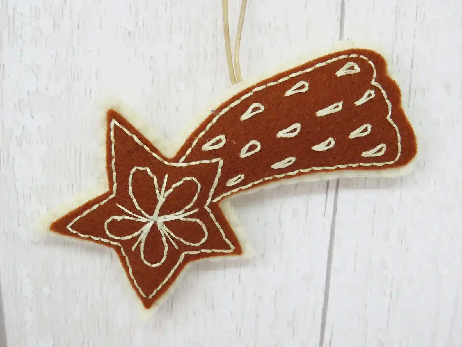 Decorative star-shaped cookie with white floral design on a light wooden surface