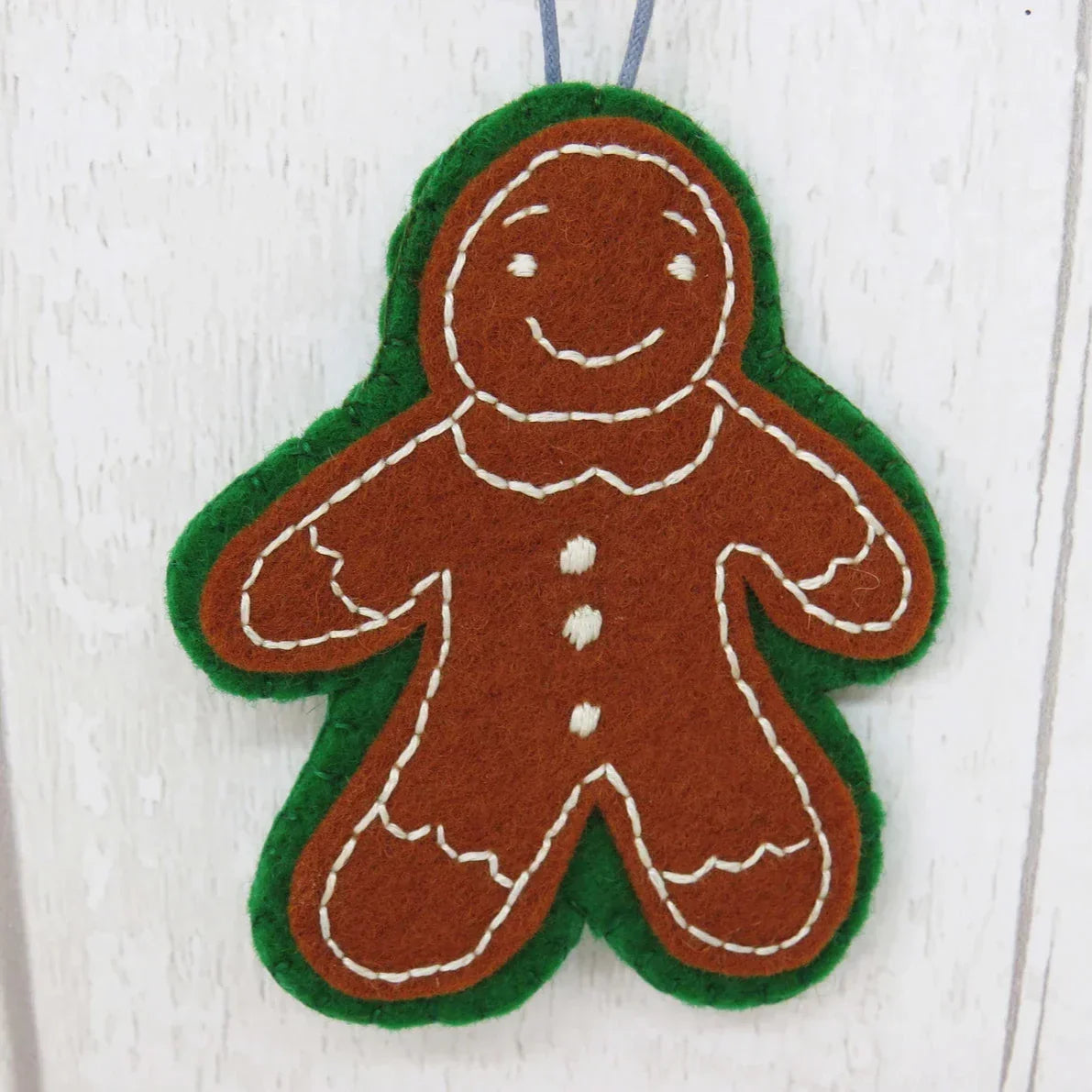 Felt gingerbread man ornament on a white wooden background