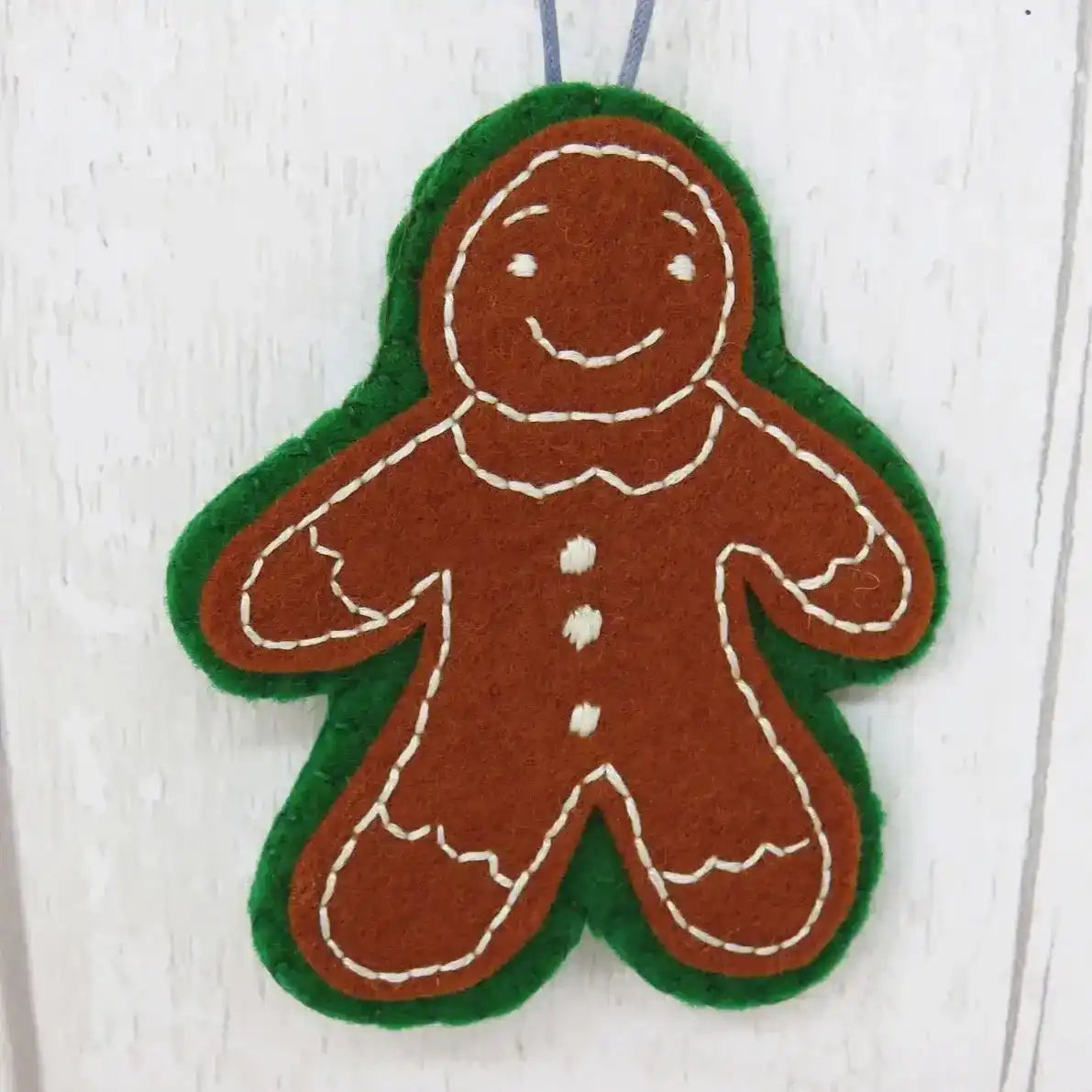 Felt gingerbread man ornament on a white wooden background