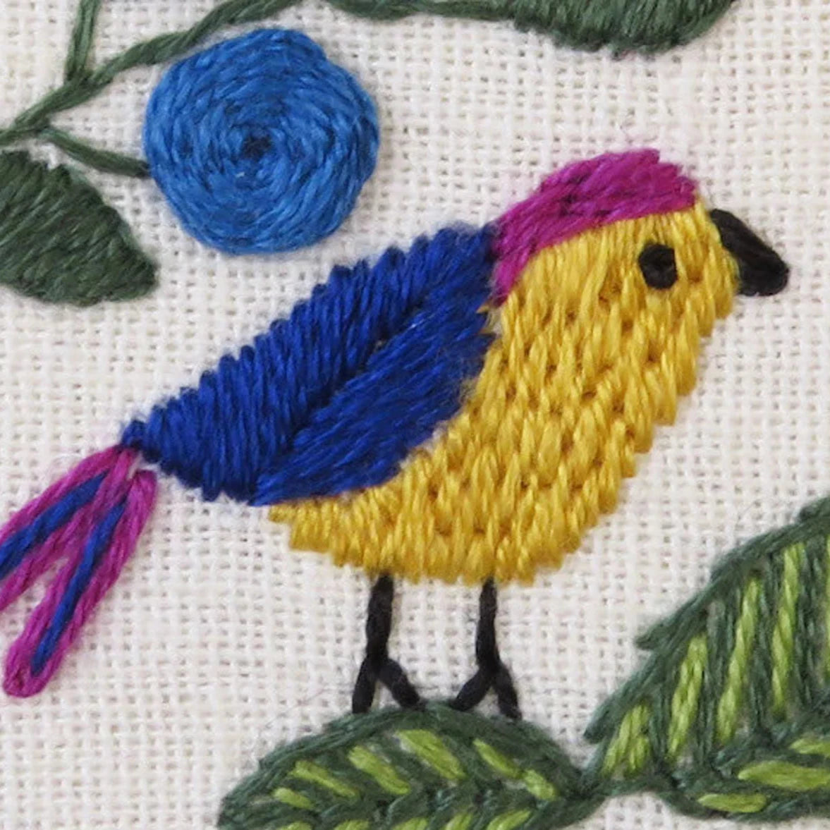 Embroidered design of a bird with blue, yellow, and pink colors on a white background.
