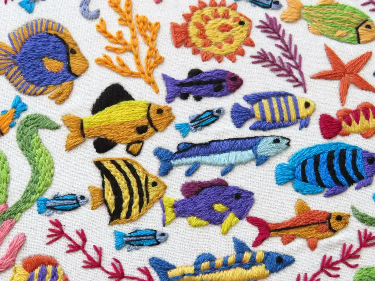 Embroidered pattern of colorful fish and sea creatures on a white background