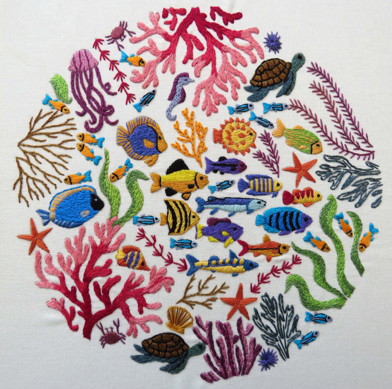 Embroidered design of colorful fish, coral, and sea creatures on a white background
